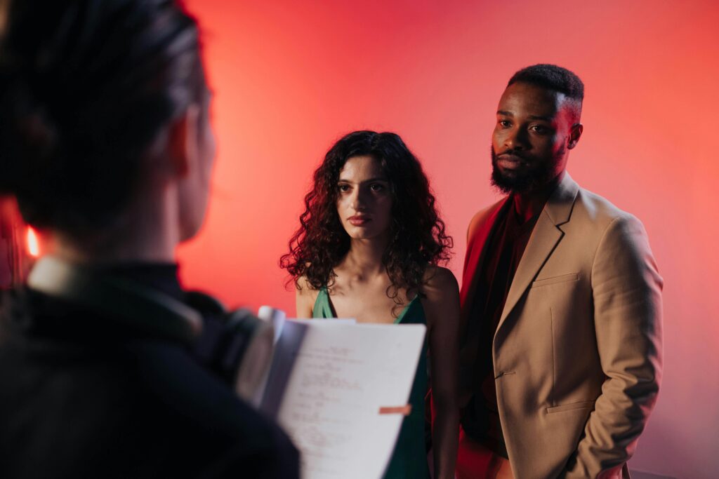 Couple reading practice acting scripts in a studio with warm lighting for film or theater production.