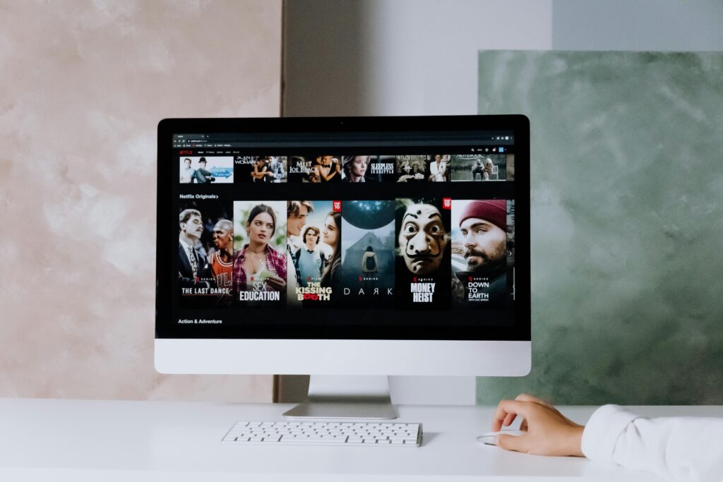 A modern workspace featuring a desktop screen displaying popular streaming series on Netflix. An actor is studying and watching movies while treating them as their own personal free acting classes.