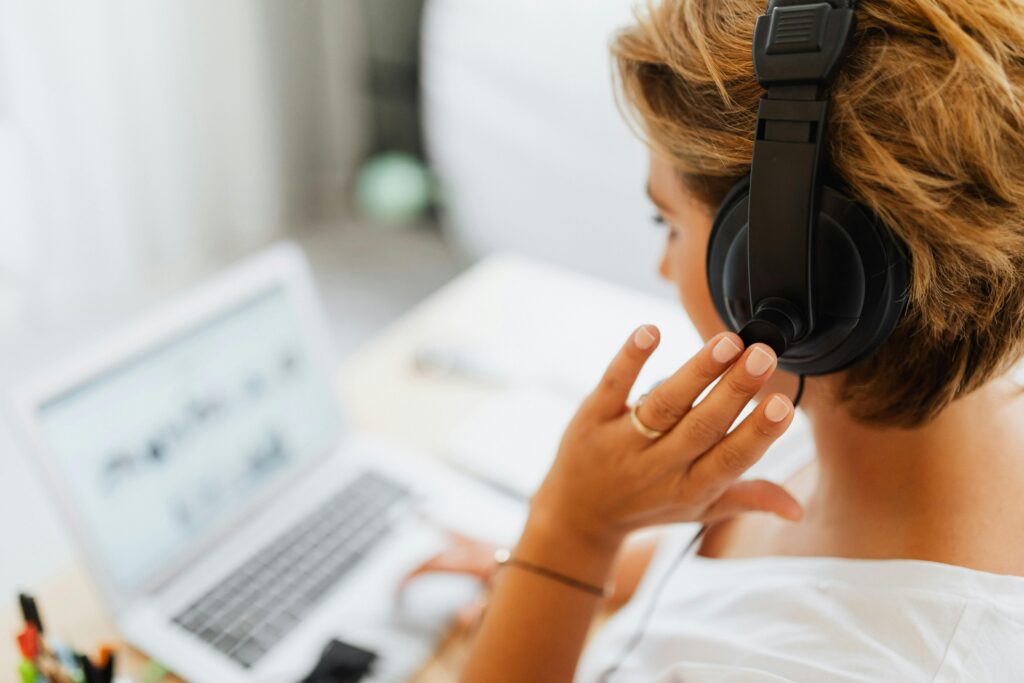 Woman at home using headphones and laptop for watching online free acting classes.