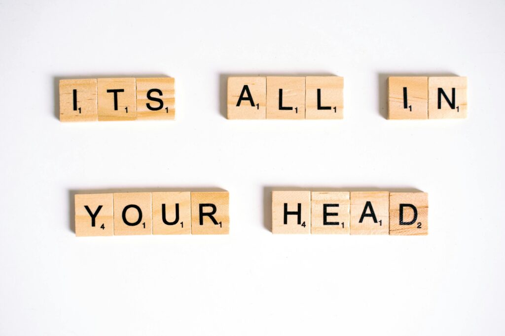 Words of Wisdom Wooden Scrabble tiles arranged to spell 'ITS ALL IN YOUR HEAD' on a white background.