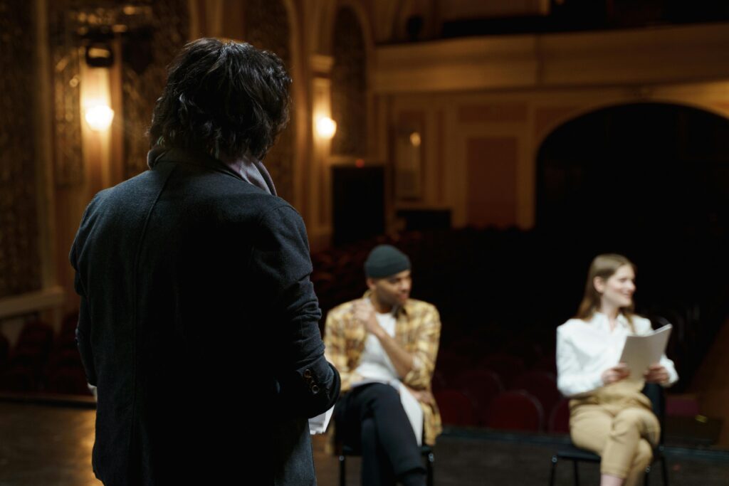 Actors in acting classes rehearse on a classical theater stage with scripts before performance.