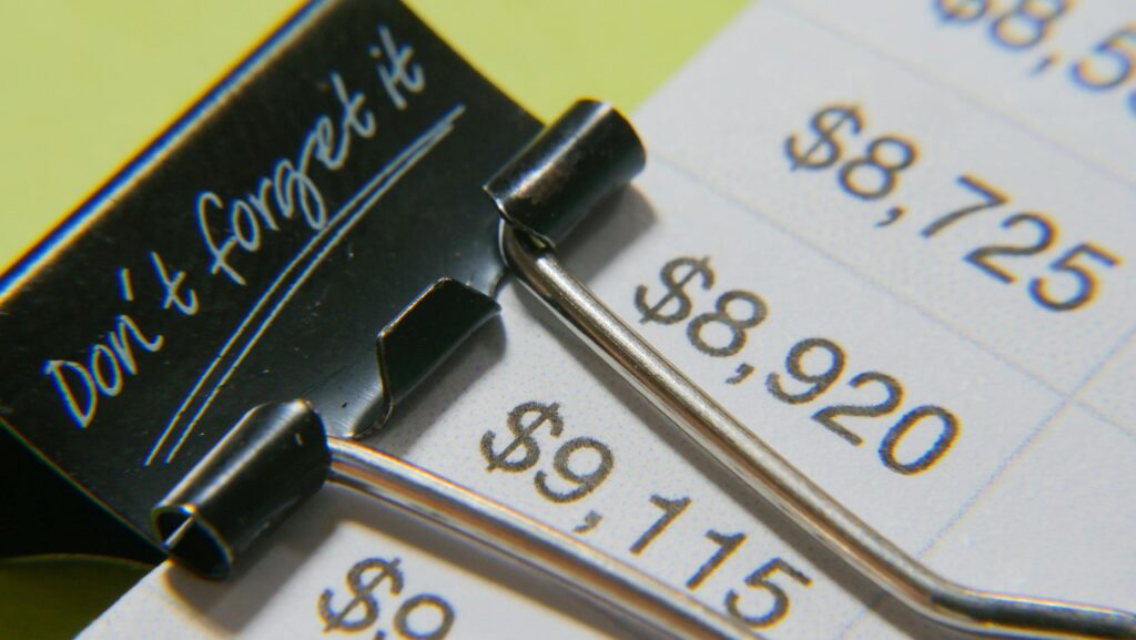 Close-up image showcasing a binder clip on a detailed financial report with highlighted amounts showing the cost of acting. Don't forget it!