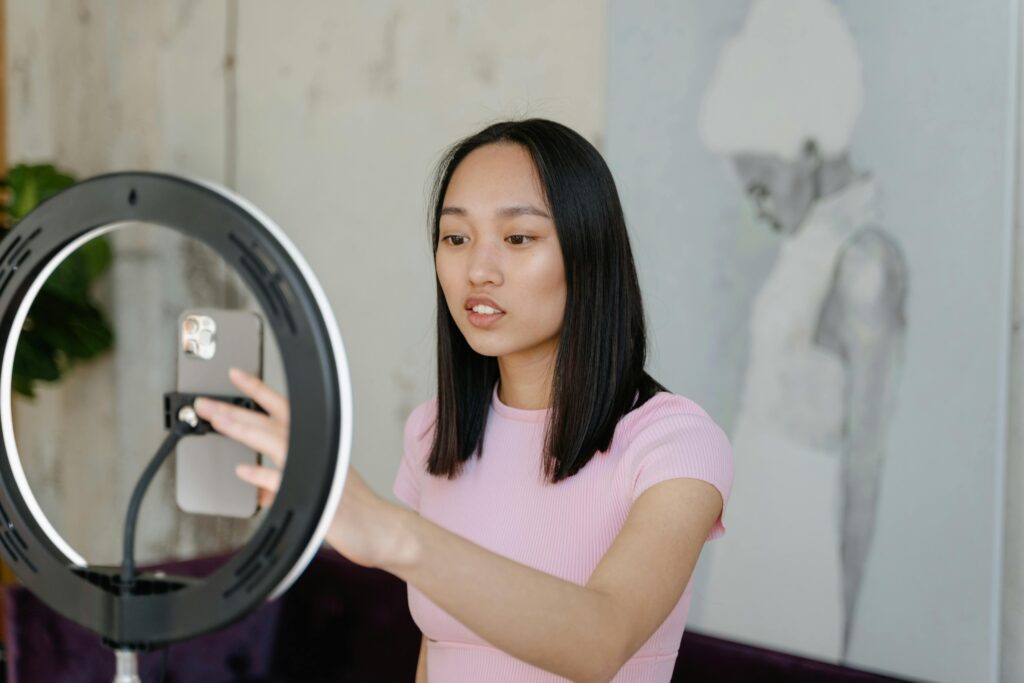 Actor using a smartphone and ring light for participating in her free and paid acting classes.