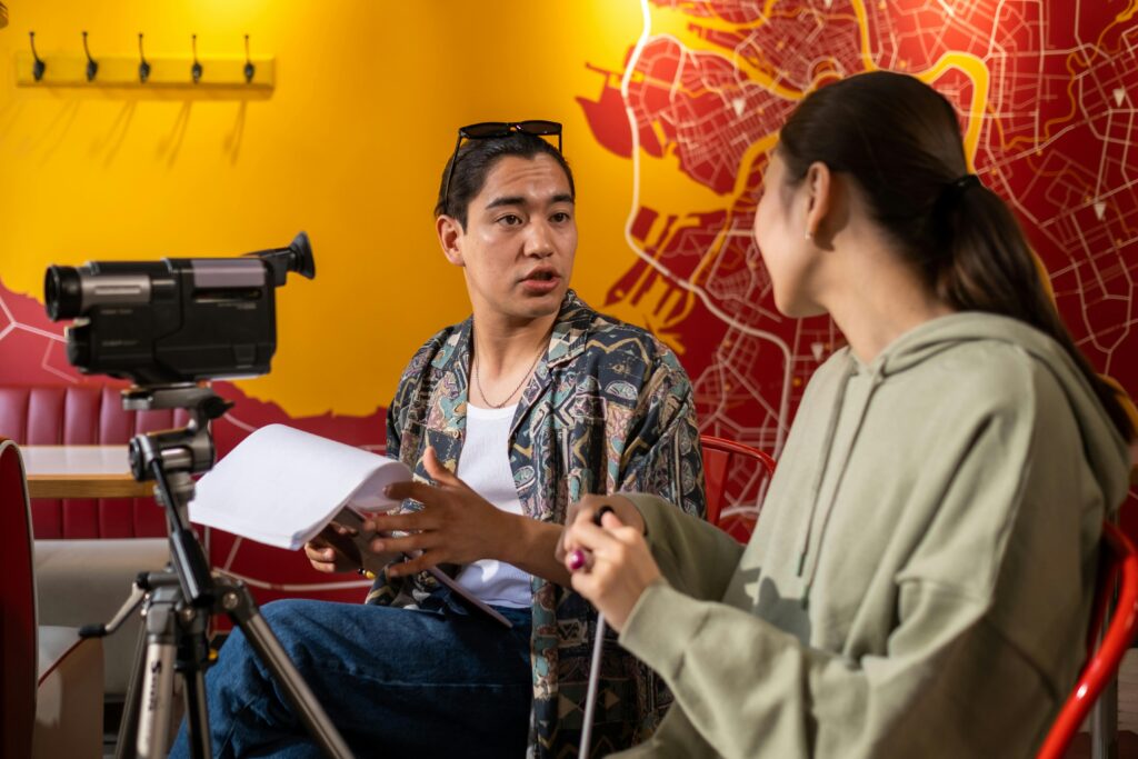 Young actors and filmmakers in active discussion during a video shoot indoors for their acting classes.