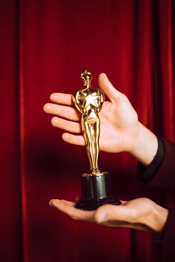 Elegant golden figurine trophy presented against a vibrant red curtain backdrop.